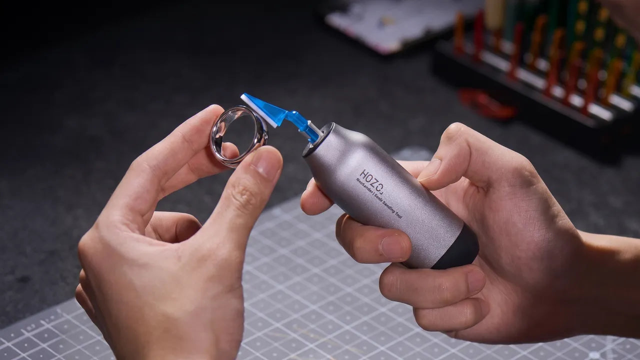 HOZO NeoSander handheld sonic sanding tool polishing handmade silver ring on leather‑craft work mat