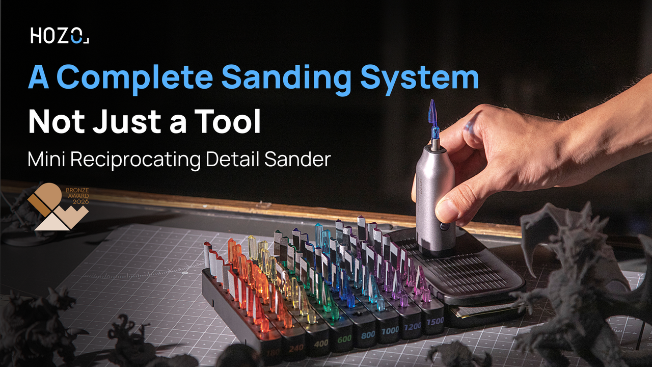 A hand holds the award-winning NeoSander mini reciprocating detail sander above its organized storage base, displaying multiple colorful interchangeable sanding heads for precision work.